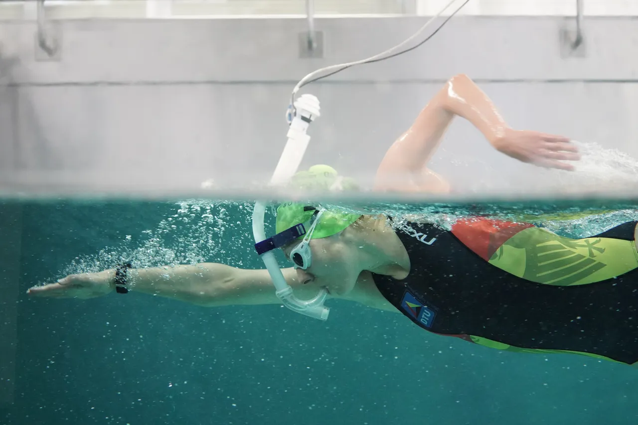 Swimmer doing front crawl in a swim flume, connected to the breath gas measurement of the METAMAX® 3B via the Swim Option